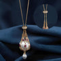 Gold pearl pendant necklace with ruby accents, featuring a large pearl encased in a gold chain cage with a smaller pearl drop